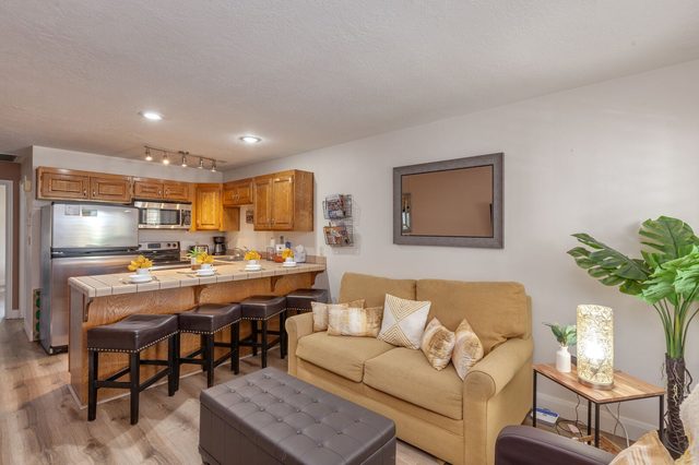 Living room sofa and ottoman open to the kitchen breakfast bar