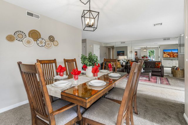 Second wood dining table with six chairs next to living area