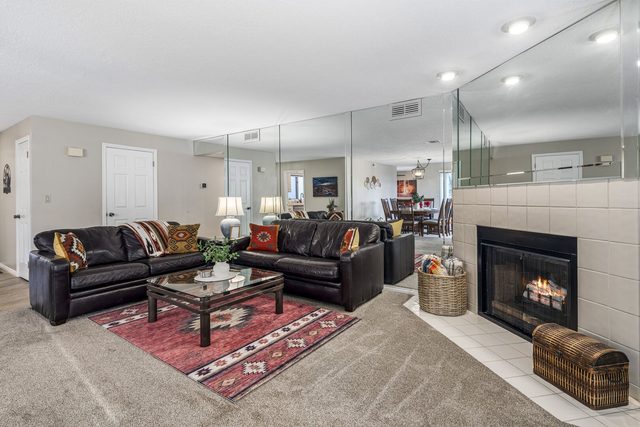 Leather sectional seating around fireplace with mirrored wall in living room