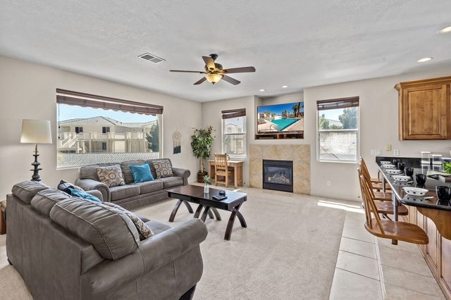 Living room seating around a gas fireplace next to the kitchen bar