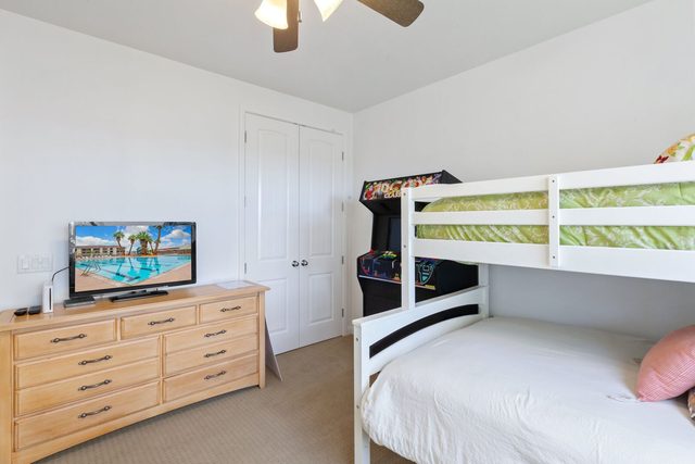 Bunk room with dresser, TV and classic arcade machine
