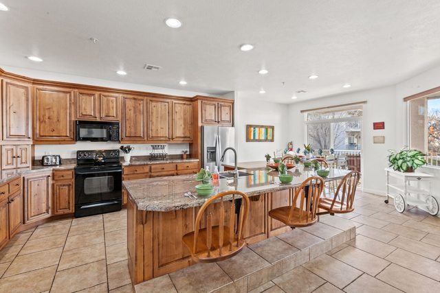 Kitchen with granite island seating and black appliances
