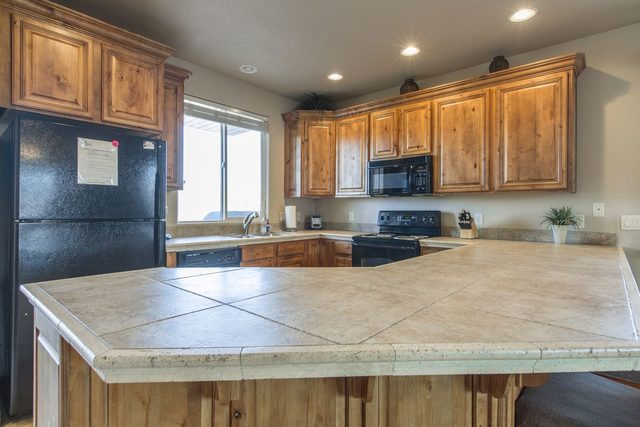 Kitchen with wood cabinets, black appliances and tiled counters
