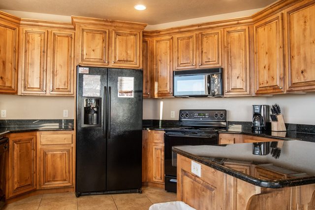 Kitchen with wood cabinets, black refrigerator and electric range