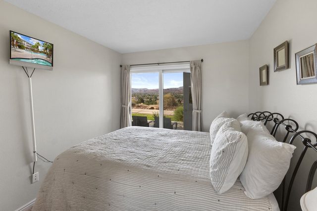 Queen bed with wall TV and patio door at Las Palmas 304