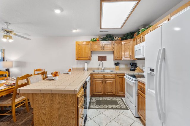 Kitchen with tiled peninsula, oak cabinets, skylight and white refrigerator