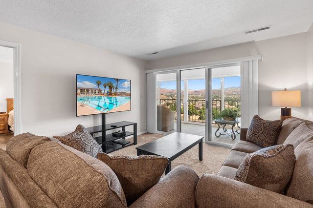 Cozy living room seating with TV stand and bright balcony doors
