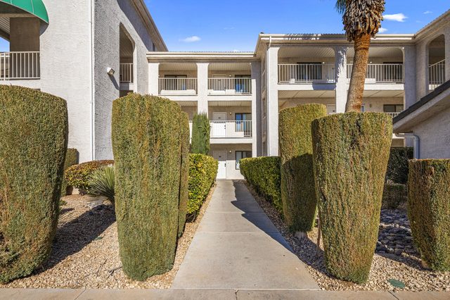 Walkway lined with hedges leading to the condo building