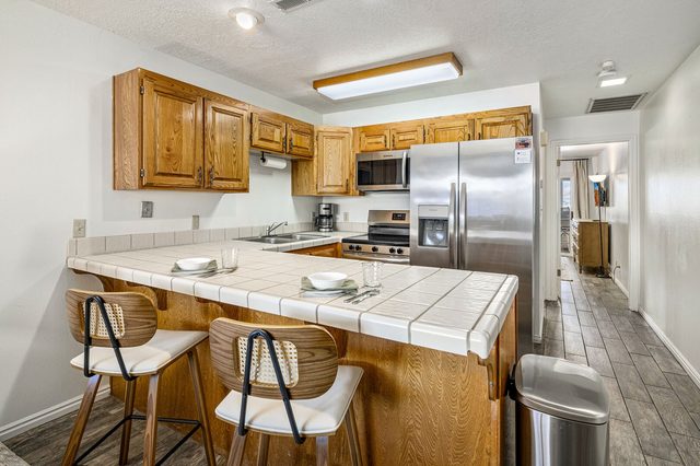 Kitchen breakfast bar with two stools and stainless refrigerator