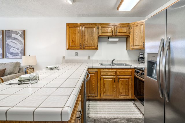 Tiled kitchen counter with stainless refrigerator and oven