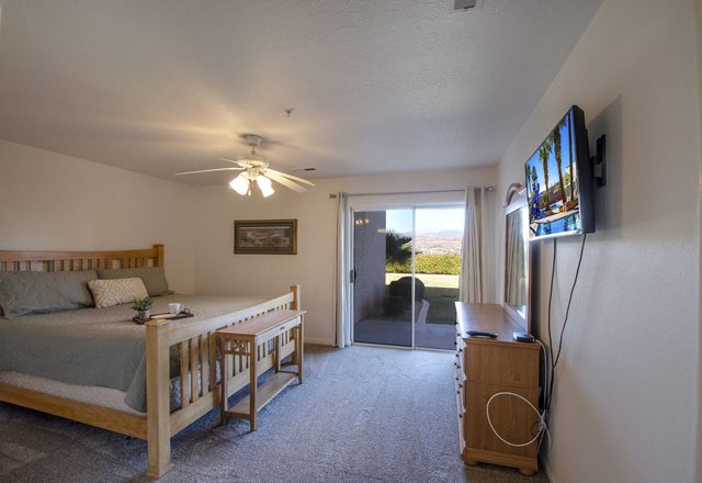 Bedroom with wood bed, wall TV and sliding door to patio