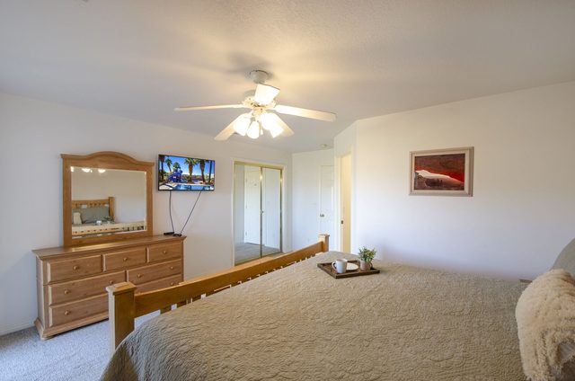 Bedroom with wood dresser, mirror and wall-mounted TV