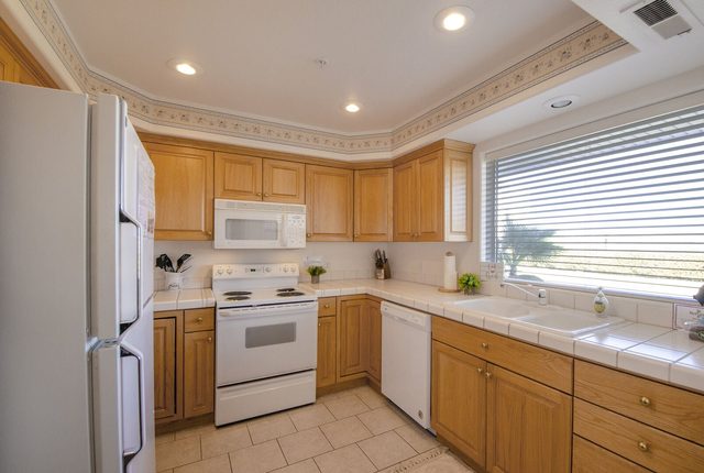 Kitchen with oak cabinets, white appliances and window over sink