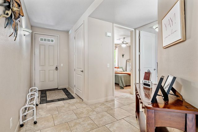 Tiled entry hallway with front door and view into a bedroom
