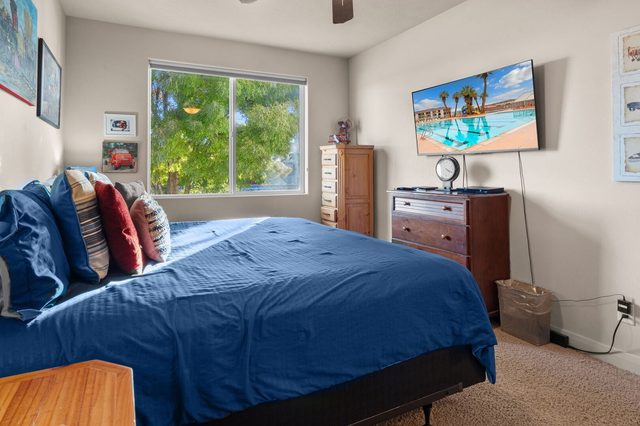 Bedroom with blue bedspread, dresser and wall-mounted TV