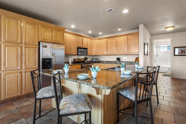 Kitchen with granite island, bar seating and stainless steel refrigerator