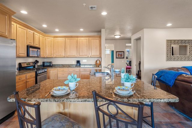 Granite kitchen island with four bar chairs and wood cabinetry