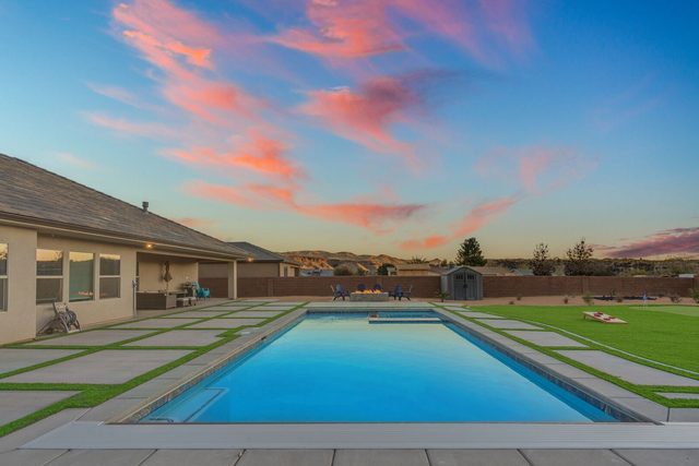 Private pool and turf-lined deck at sunset behind the house