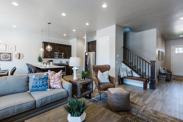Living area sofa and armchair with kitchen and stairs behind