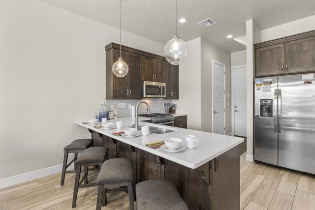Kitchen with island bar seating and stainless steel refrigerator