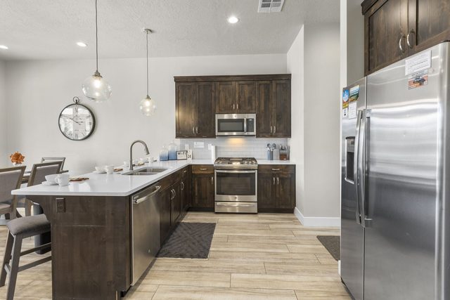Kitchen with dark wood cabinets, gas range and pendant lights