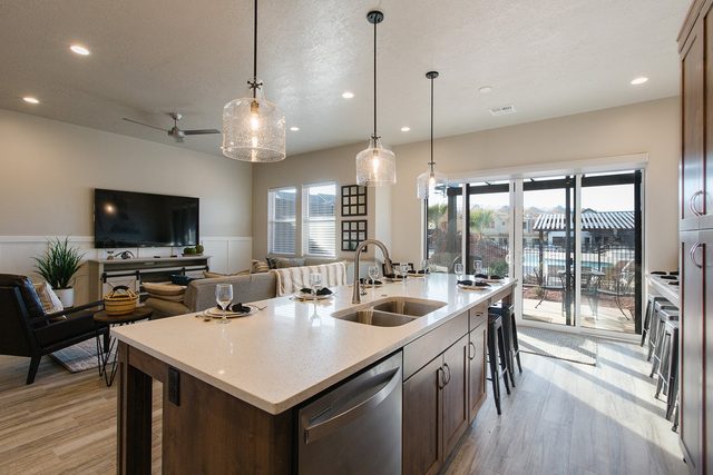 Kitchen island with sink and pendant lights facing the living area