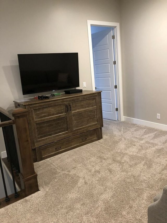 Carpeted upstairs loft with TV and wood cabinet
