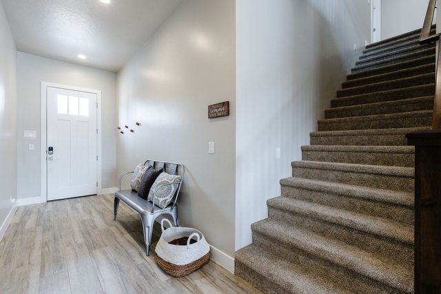 Entry with front door, bench and carpeted staircase