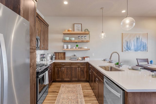 Kitchen with stainless range, dishwasher and open wood shelving