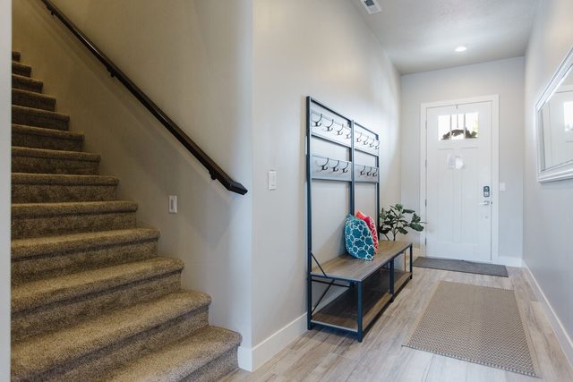 Entry with bench, coat rack and carpeted staircase