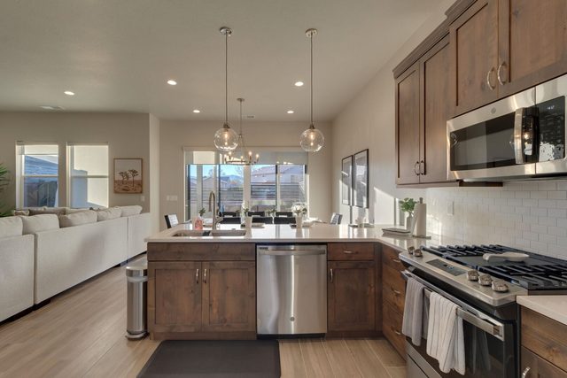 L-shaped kitchen with dishwasher and gas range beside living room