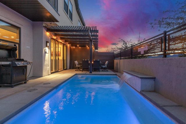 Private pool lit blue at twilight beside the covered patio