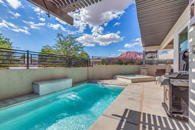 Private pool, raised spa and gas grill under blue sky