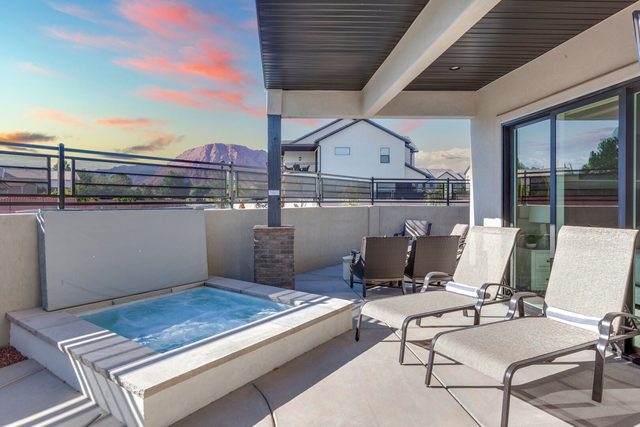 Raised private spa beside pool loungers under covered patio