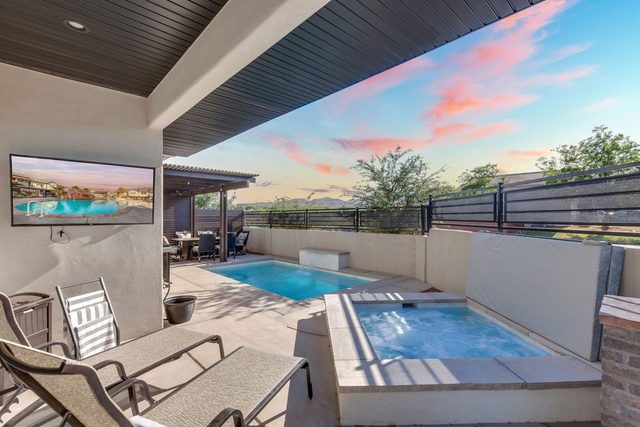 Private spa and pool viewed from covered patio with TV