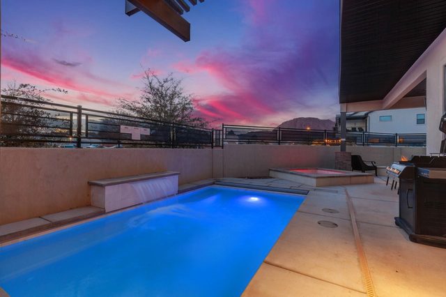 Private pool lit at dusk with spa and grill