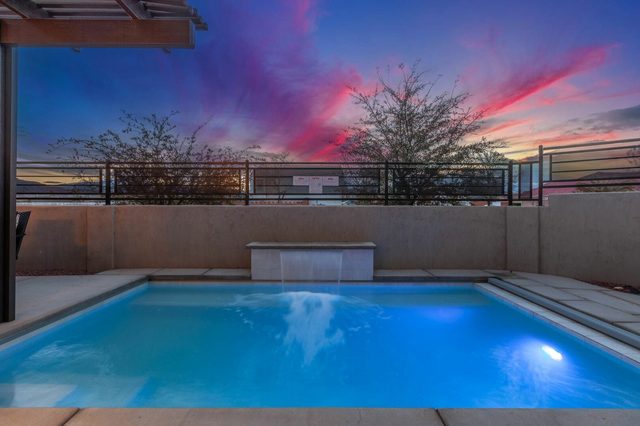 Private pool waterfall glowing blue under a sunset sky