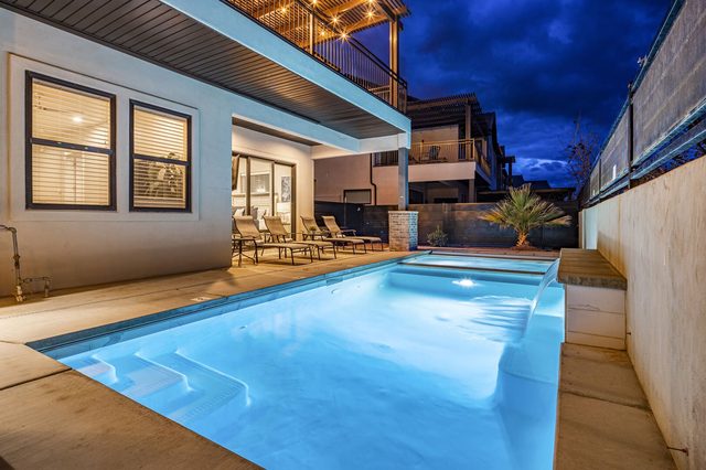 Lit private pool with steps and lounge chairs at night