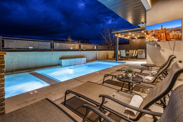 Private pool lounge chairs and outdoor TV at twilight