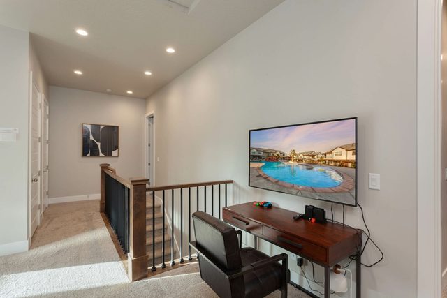 Loft workspace desk with smart TV above the stair railing