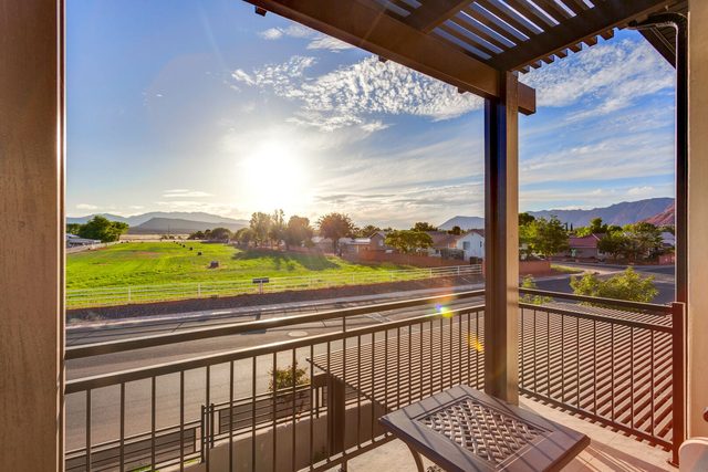 Balcony view over green fields toward distant mountains
