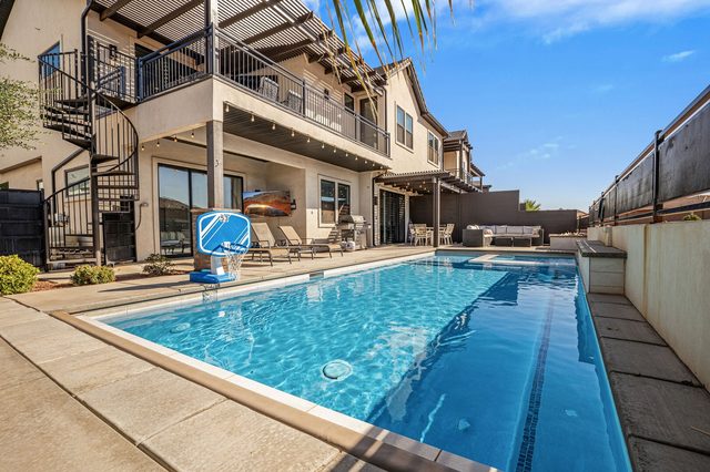 Private pool with basketball hoop below spiral stairs and balcony