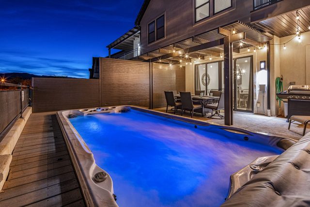 Lit private swim spa beside the covered patio at twilight