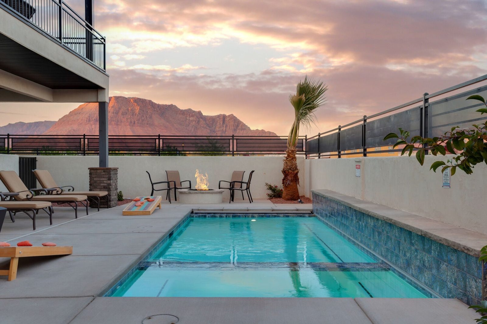 Private pool with lounge chairs and red rock mountains at sunset