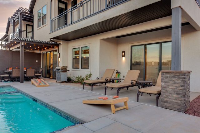 Private pool with lounge chairs and cornhole beside the house