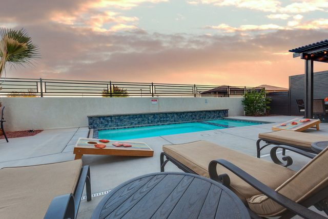 Private pool with cornhole boards and lounge chairs