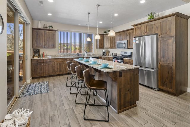Kitchen with wood cabinets, island bar stools and stainless fridge at Paradise Village 10