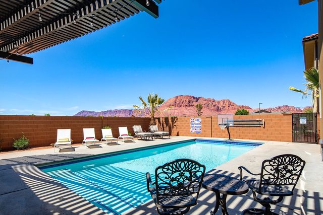 Private pool with wrought-iron chairs and red cliff views