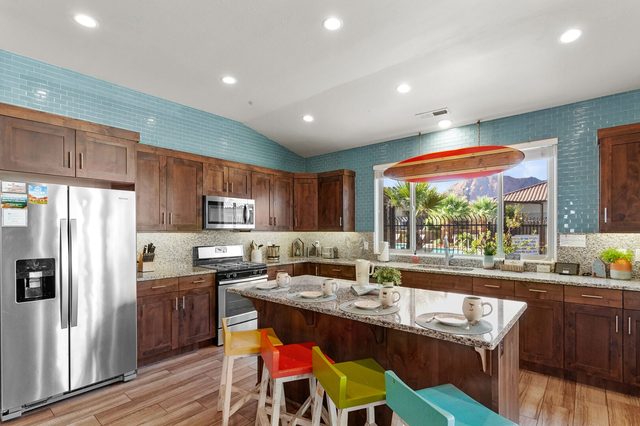 Kitchen island with colorful bar stools and stainless appliances at Paradise Village 110