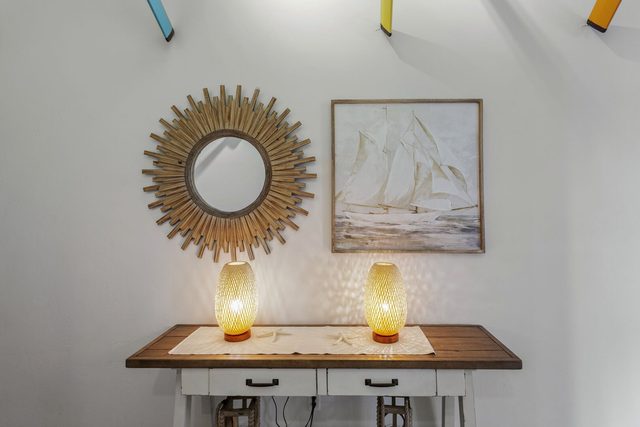 Entry console with sunburst mirror and sailboat artwork